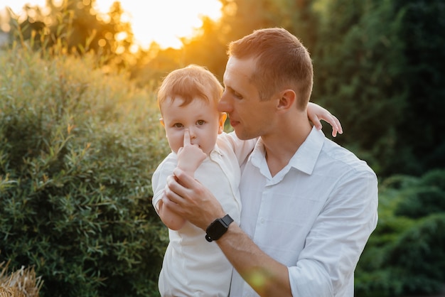 Père et fils marchant dans le parc au coucher du soleil. Bonheur. L'amour