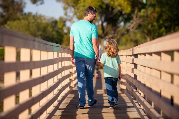 Père avec fils marchant sur un pont boisé en plein air