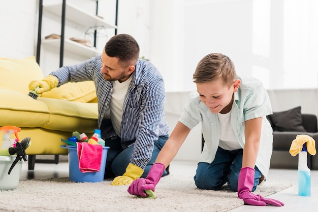 Photo père et fils nettoyant le tapis