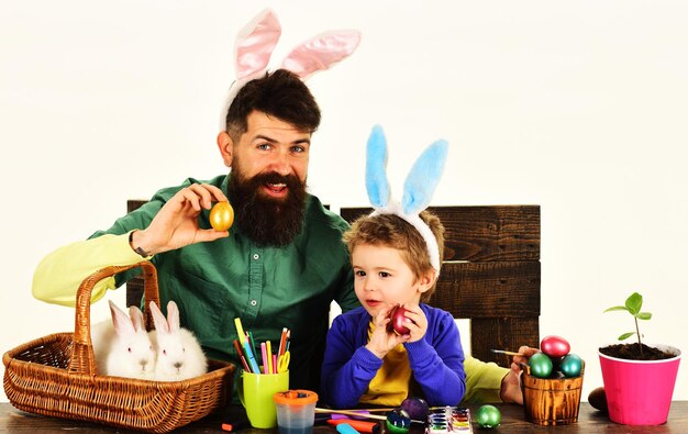 Père et fils peignant des oeufs famille heureuse se préparant pour les vacances de pâques oeuf décoré pour les vacances