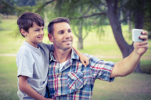 Photo père et fils prenant un selfie dans le parc