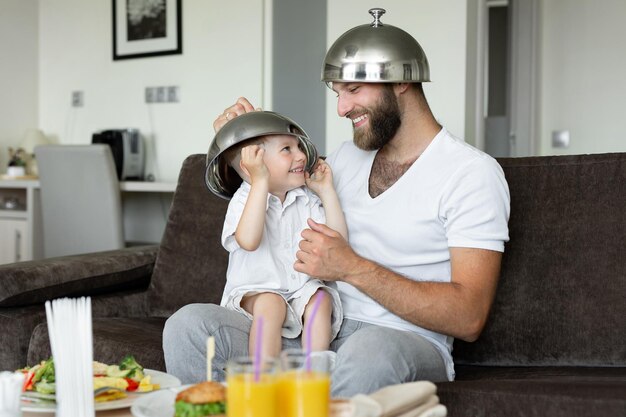 Père et fils prennent le petit déjeuner dans une chambre d'hôtel et se livrent à rire