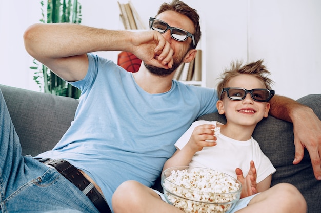 Père et fils, regarder des films à la maison dans des lunettes 3D et manger du pop-corn