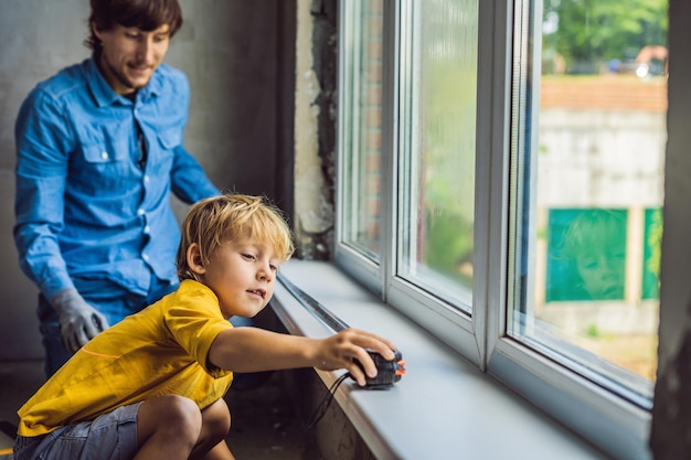 Père et fils réparent les fenêtres ensemble. Réparez la maison vous-même.