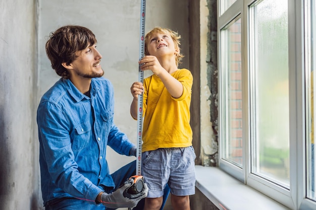 Père et fils réparent les fenêtres ensemble. Réparez la maison vous-même.