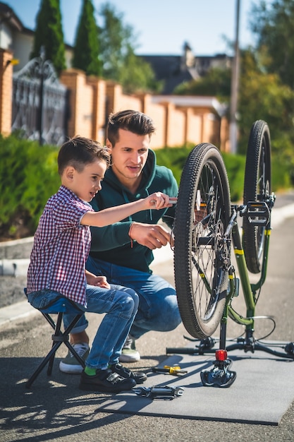 Le père et le fils réparent le vélo en plein air