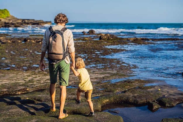 Père et fils se promènent le long de la plage cosmique de Bali. Touristes de voyage portrait - papa avec enfants. Émotions humaines positives, modes de vie actifs. Heureuse jeune famille sur la plage de la mer