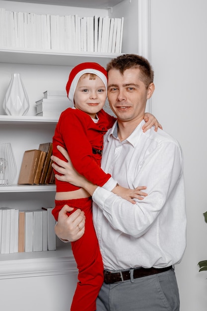 Photo père avec fils en tenue de père noël. concept de famille, vacances, génération, noël et personnes. période de noël.