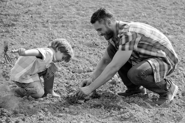 Père et fils travaillent sur la terre au sol famille plantation papa enseignant à petit garçon à faire du jardinage