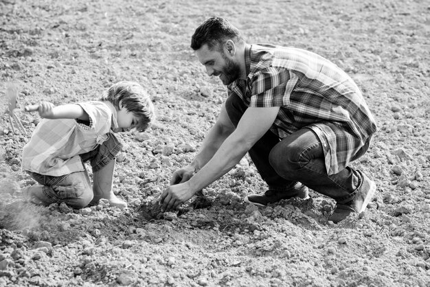 Photo père et fils travaillent sur terre famille plantant papa apprenant au petit garçon à faire du jardinage