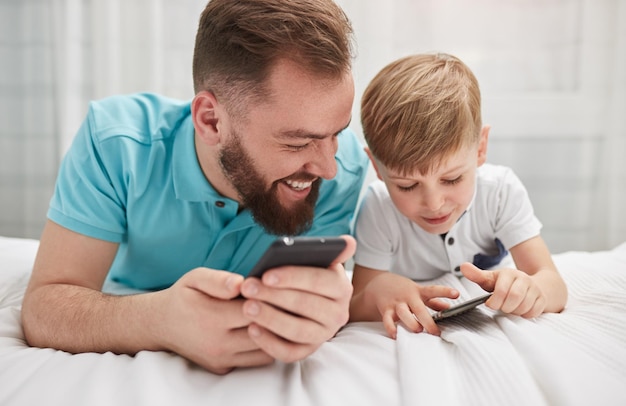 Père et fils utilisant ensemble des smartphones