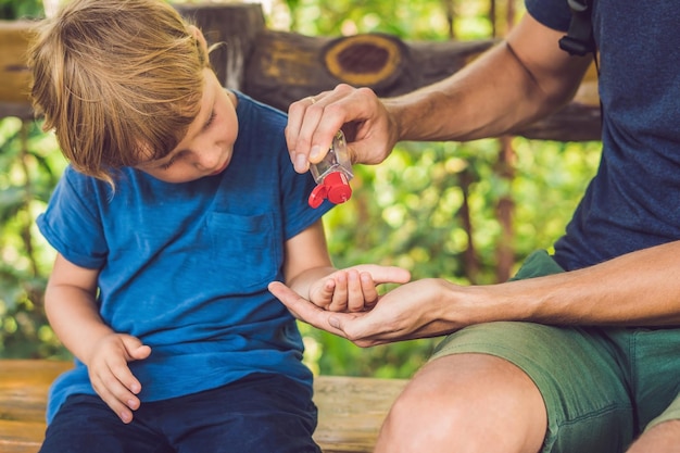 Père et fils utilisant un gel désinfectant pour les mains dans le parc avant une collation