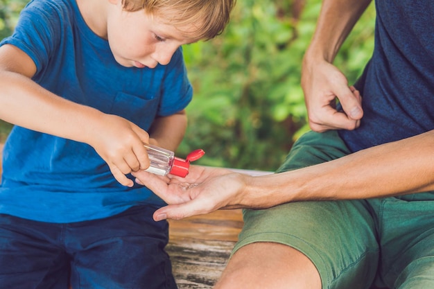 Père et fils utilisant un gel désinfectant pour les mains dans le parc avant une collation