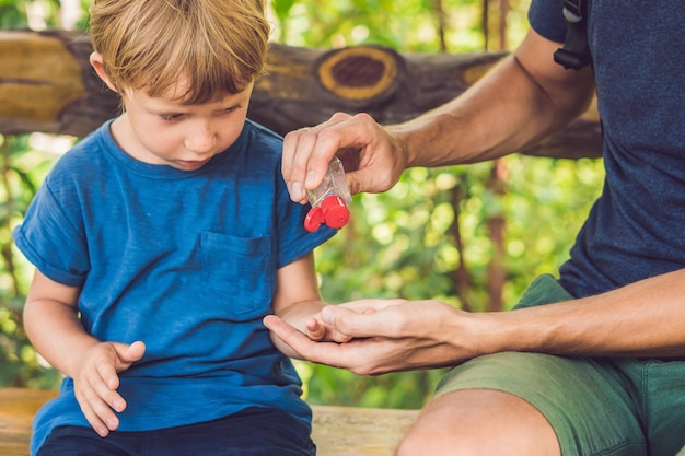 Père et fils utilisant un gel désinfectant pour les mains dans le parc avant une collation