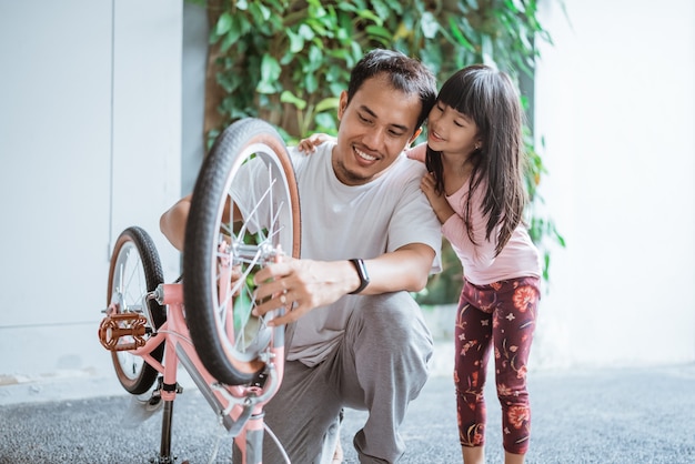 Père fixant des roues de bicyclette avec sa fille