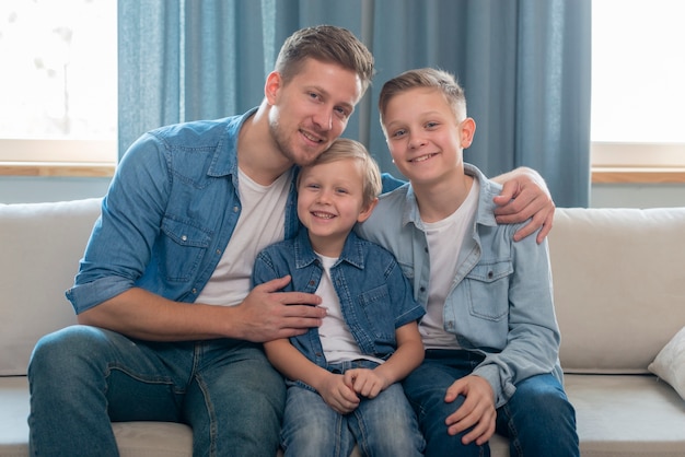 Père et frères mignons assis sur le canapé