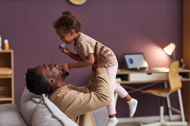 Père heureux jouant avec sa petite fille et la tenant en l'air