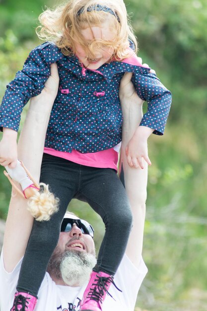 Photo un père heureux portant une jolie fille.