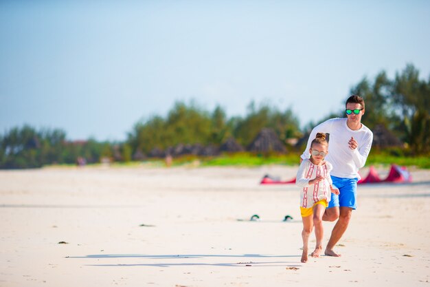 Père heureux et sa petite fille adorable à la plage tropicale s'amuser