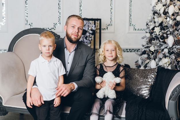 Père avec un jeune fils et sa fille à l'arbre de Noël
