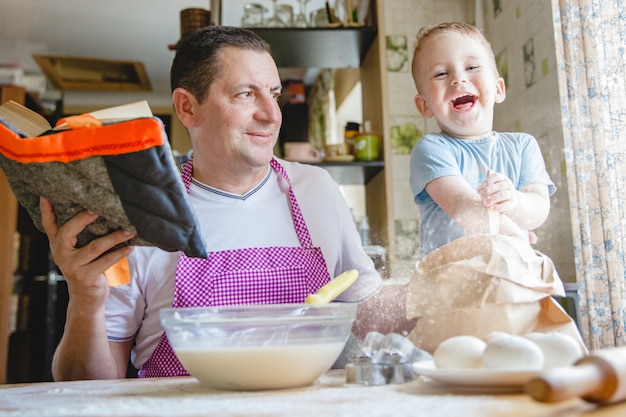 Un père avec un jeune fils à la table de cuisine préparer la pâte