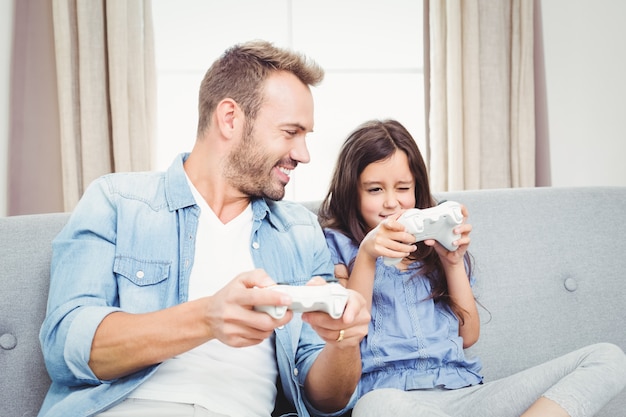 Père jouant à un jeu vidéo avec sa fille à la maison