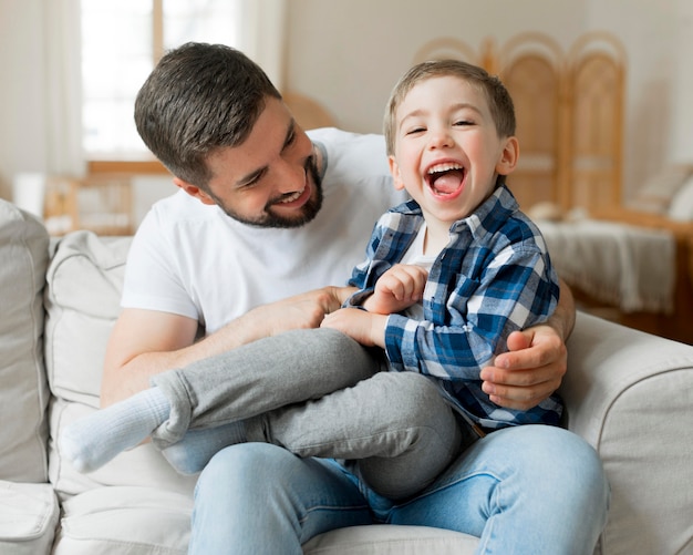 Père jouant avec son fils sur le canapé