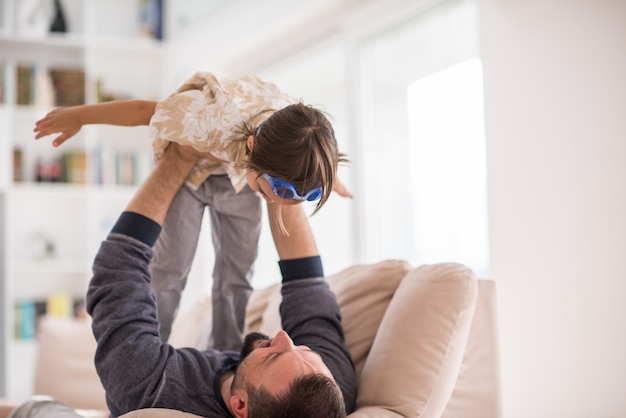 Père jouant avec son petit fils sur le canapé à la maison