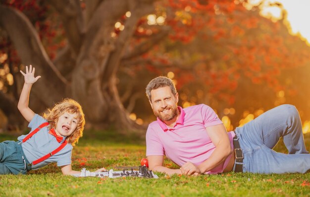 Un père joue aux échecs avec une famille de fils excités et étonnés à l'extérieur du jeu