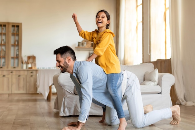 Un père joue avec sa petite fille à l'intérieur.