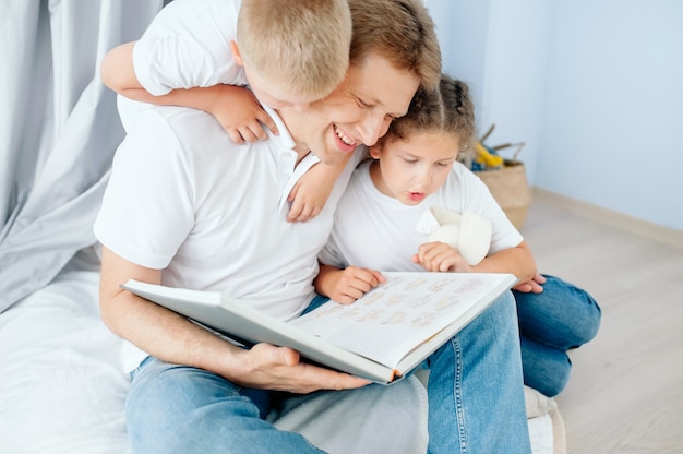 père lisant un livre à ses enfants fille et fils