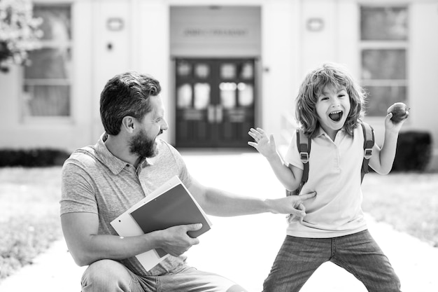 Père marchant fils à l'école Parent et élève d'écolier de l'école primaire avec sac à dos à la cour de l'école