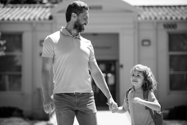 Père marchant fils à l'école parent et élève de l'écolier de l'école primaire avec sac à dos parent mène