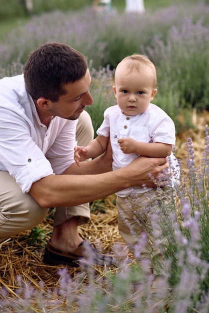 Un père marche sur un champ de lavande avec son fils.