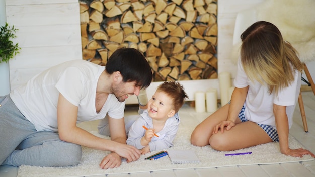 Père et mère aidant leur enfant à faire un dessin dans leur salon