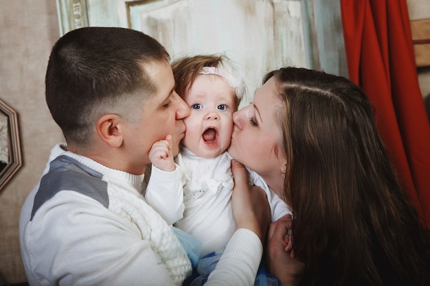 Père et mère embrassent le bébé. Notion de famille.