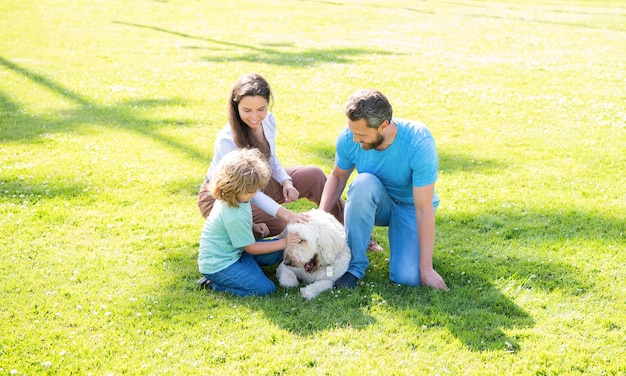 Père mère et enfant sur l'herbe verte du parc. famille sympathique avec animal de compagnie.