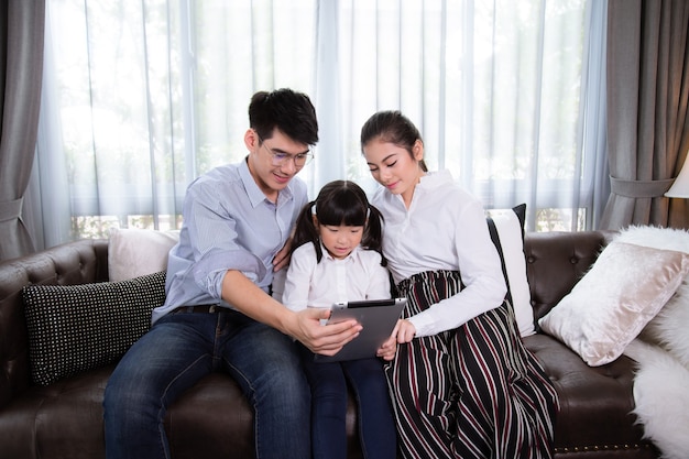 Père et mère Enseigner aux enfants à utiliser une tablette pour faire leurs devoirs à la maison La famille asiatique est heureuse