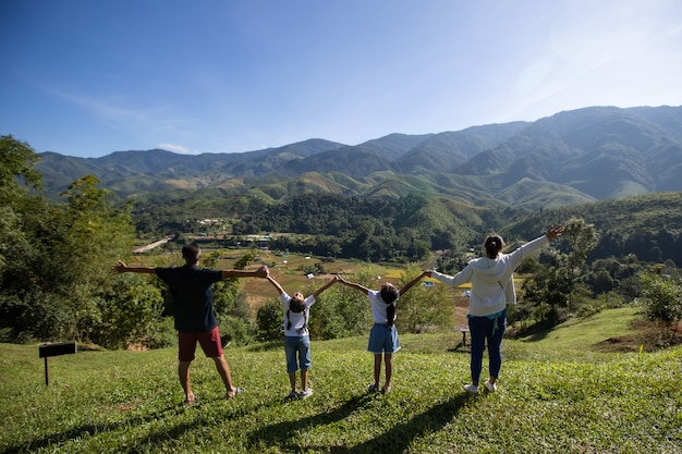 Père, mère et filles asiatiques lèvent les bras en regardant la belle montagne