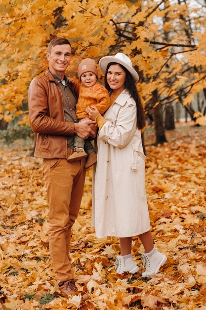 Père et mère avec fils marchant dans le parc de l'automne. Une famille se promène dans l'automne doré dans un parc naturel.