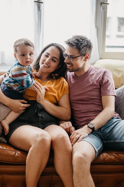 Un père et une mère avec leur fils assis sur le canapé à la maison