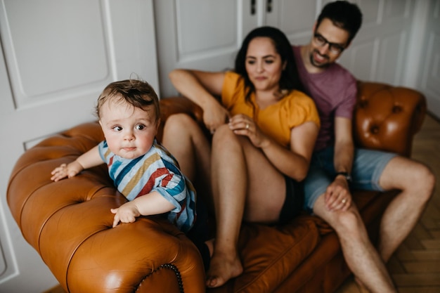 Un père et une mère avec leur fils assis sur le canapé à la maison