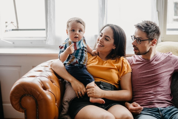 Un père et une mère avec leur fils assis sur le canapé à la maison