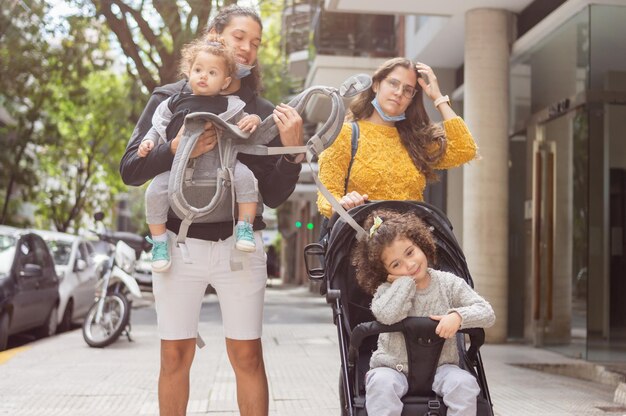 père et mère marchant avec leurs filles sur le trottoir