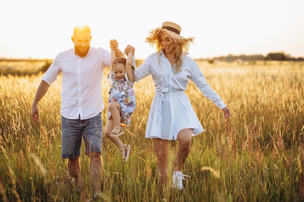 Photo père et mère avec petite fille marchant dans le pré