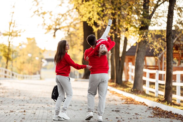 Père, mère et petite fille marchent dans le parc d'automne, une famille heureuse s'amuse à l'extérieur.