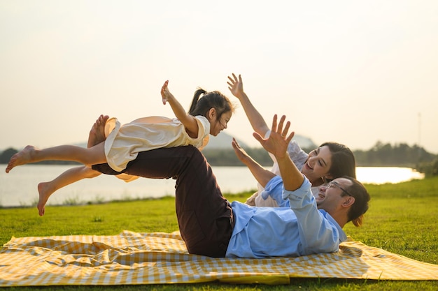 Père et mère souriants passent du temps à voyager avec des enfants au parc