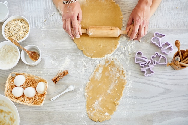 Père montrant à sa petite fille comment rouler la pâte pour les cookies