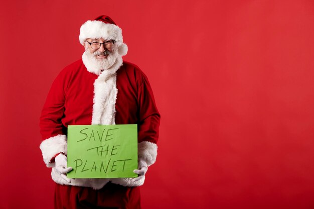 Photo le père noël avec une affiche de sauvetage de la planète sur fond rouge