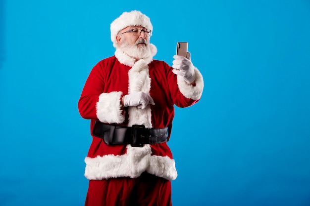 Père Noël à l'aide d'un téléphone mobile sur fond bleu